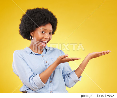 Space, portrait of a black woman in studio showing mockup for advertising or marketing. Happy, smile and face of African female model pointing to mock up for product placement by yellow background. Space, portrait of a black woman in studio showing mockup for advertising or marketing. Happy, smile and face of African female model pointing to mock up for product placement by yellow background. 133017952