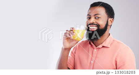 Orange juice, portrait and happy black man drinking with glass for hydration, liquid detox or weight loss. Vitamin C benefits, male nutritionist beverage and studio person on mockup gray background 133018203