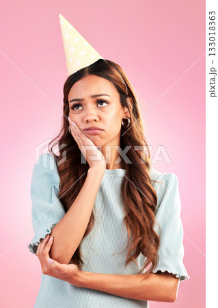 Sad, birthday and hat with woman in studio for party celebration, upset and annoyed. Alone, disappointed and failure with female isolated on pink background for moody, difficulty and frustrated Sad, birthday and hat with woman in studio for party celebration, upset and annoyed. Alone, disappointed and failure with female isolated on pink background for moody, difficulty and frustrated 133018363