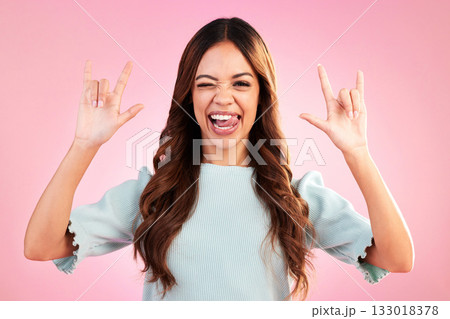 Portrait of woman, rock hand gesture and wink in studio, heavy metal expression on face and pink background. Crazy, wild hispanic model and hands in devil horn sign with punk attitude and happy smile Portrait of woman, rock hand gesture and wink in studio, heavy metal expression on face and pink background. Crazy, wild hispanic model and hands in devil horn sign with punk attitude and happy smile 133018378