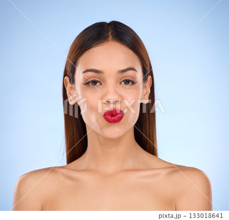 Woman, beauty and red lipstick makeup portrait with cosmetics on face in studio. Aesthetic female model on a blue background for self care, facial glow and shine or color for lips and skin wellness Woman, beauty and red lipstick makeup portrait with cosmetics on face in studio. Aesthetic female model on a blue background for self care, facial glow and shine or color for lips and skin wellness 133018641