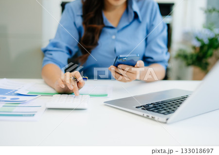 Women counting coins on calculator taking from the piggy bank. hand holding pen working on calculator to calculate on desk about cost 133018697