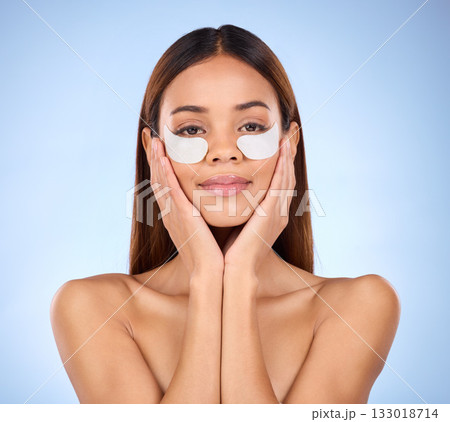 Beauty, collagen and portrait of woman with eye mask for anti aging skincare glow on blue background. Cosmetics, facial repair and face of hispanic model with wrinkle treatment product in studio. Beauty, collagen and portrait of woman with eye mask for anti aging skincare glow on blue background. Cosmetics, facial repair and face of hispanic model with wrinkle treatment product in studio. 133018714