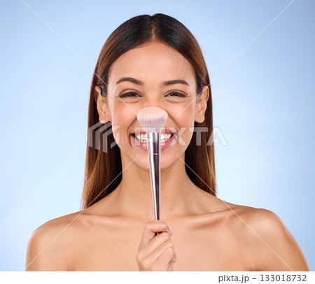 Beauty, makeup and brush on nose of woman in studio for cosmetics, satisfaction and self care. Glow, foundation and blush with girl model on blue background for facial, powder and cosmetology product 133018732