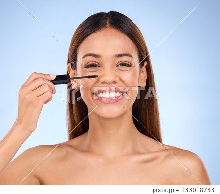 Beauty portrait, woman and mascara makeup with a smile for cosmetics on face in studio. Female model on blue background for self care, facial glow and eyelash extension or growth with luxury product 133018733