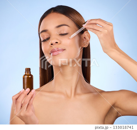 Beauty, skincare and cosmetics, hispanic woman with serum in pipette for anti aging skin glow on blue background. Makeup, facial repair and face of model with solution or collagen product in studio. Beauty, skincare and cosmetics, hispanic woman with serum in pipette for anti aging skin glow on blue background. Makeup, facial repair and face of model with solution or collagen product in studio. 133018741