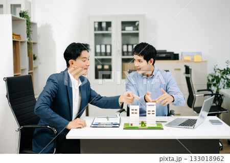 Two professional men analyzing house model and design layout in office. Ideal for themes of architecture, investment, real estate, property 133018962