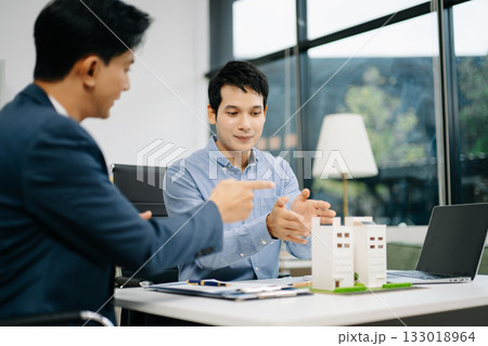 Two professional men analyzing house model and design layout in office. Ideal for themes of architecture, investment, real estate, property Two professional men analyzing house model and design layout in office. Ideal for themes of architecture, investment, real estate, property 133018964