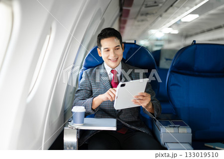 Portrait of a successful Asian businesswoman or entrepreneur in a formal suit on an airplane sitting in business class using a phone, computer laptop. Travel in style, work with grace. Portrait of a successful Asian businesswoman or entrepreneur in a formal suit on an airplane sitting in business class using a phone, computer laptop. Travel in style, work with grace. 133019510