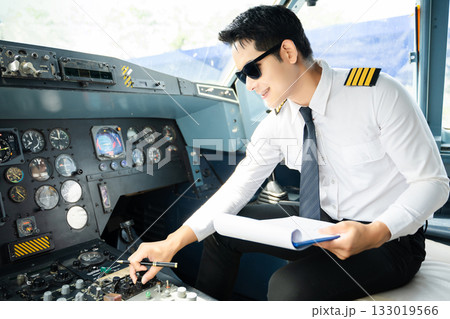 Professional airline pilot in uniform inspecting cockpit control panels during safety checks, ideal for aviation, travel, and airline safety themes. Professional airline pilot in uniform inspecting cockpit control panels during safety checks, ideal for aviation, travel, and airline safety themes. 133019566
