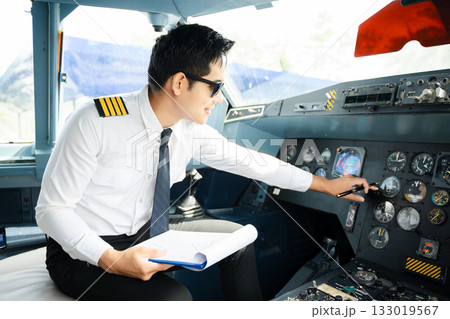 Professional airline pilot in uniform inspecting cockpit control panels during safety checks, ideal for aviation, travel, and airline safety themes. Professional airline pilot in uniform inspecting cockpit control panels during safety checks, ideal for aviation, travel, and airline safety themes. 133019567
