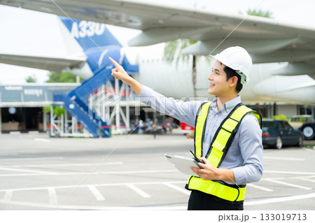 Ground crew engineer in safety vest and hard hat using walkie talkie while checking documents, perfect for aviation, maintenance, Ground crew engineer in safety vest and hard hat using walkie talkie while checking documents, perfect for aviation, maintenance, 133019713
