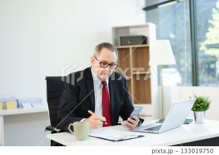 Mature business man executive manager looking at laptop watching online webinar training or having virtual working in office. Mature business man executive manager looking at laptop watching online webinar training or having virtual working in office. 133019750