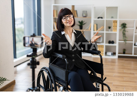 Caucasian woman, young adult, professional attire, sitting wheelchair, speaking camera business-related vlog. 133019988
