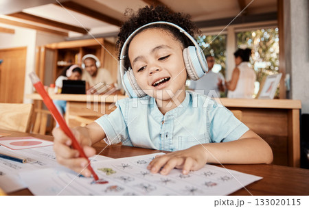 Distance learning, headphones and student doing homework while listening to music, audio book or radio. Home school, education of young kid or boy child writing on paper for academic or project 133020115