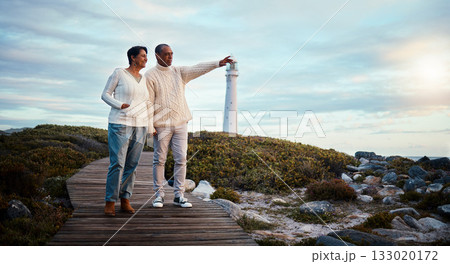 Travel, love and elderly couple pointing on boardwalk at beach, calm at a lighthouse against sunset sky. Senior, man with woman on ocean trip, holiday or vacation, happy and enjoying retirement 133020172
