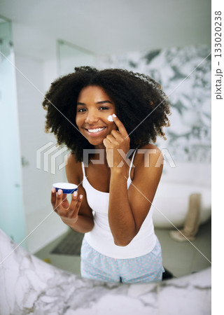 Skincare, smile and portrait of black woman in bathroom mirror with cream, dermatology and morning routine. Health, wellness and luxury skin care at home, happy girl in reflection with lotion on face 133020238
