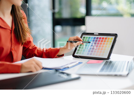 Asian graphic designer working on digital tablet with color swatches on screen. Concept of creativity, freelance design, digital content creation 133020600