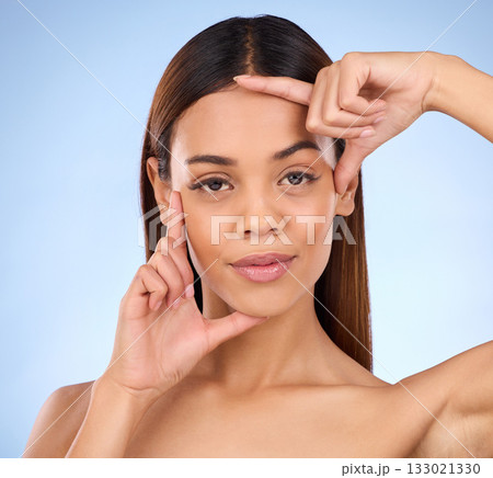 Beauty, woman and hands on face portrait for skincare dermatology cosmetics in studio. Female model person on a blue background for self care, facial glow and healthy or clean skin with finger frame Beauty, woman and hands on face portrait for skincare dermatology cosmetics in studio. Female model person on a blue background for self care, facial glow and healthy or clean skin with finger frame 133021330