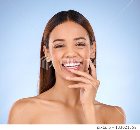Portrait, skincare and woman with laugh, cosmetics and happiness against blue studio background. Face, Latino female and lady with smile, dermatology and morning routine for confidence and soft skin 133021358