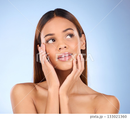 Woman, face and thinking in beauty skincare cosmetics or self love and care against blue studio background. Happy female wondering or touching perfect skin in satisfaction for facial or spa treatment Woman, face and thinking in beauty skincare cosmetics or self love and care against blue studio background. Happy female wondering or touching perfect skin in satisfaction for facial or spa treatment 133021360