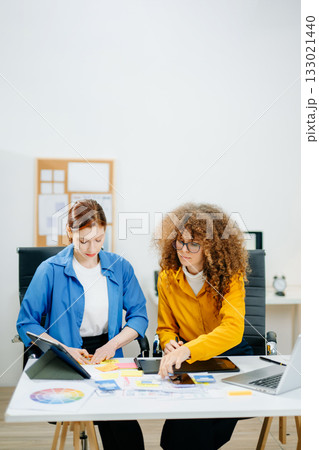 UX UI designers in modern office working on app wireframes, color palettes, and digital tools. Creative teamwork, planning, technology 133021440