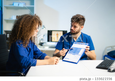 Doctor and young female patient reviewing medical form together. Concept of healthcare consultation 133021556