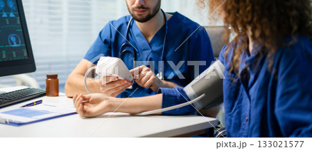 Female patient gets blood pressure checked by doctor with digital monitor. Health checkup, patient care, and medical technology Female patient gets blood pressure checked by doctor with digital monitor. Health checkup, patient care, and medical technology 133021577