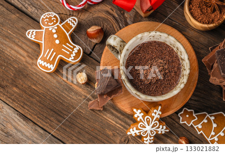 Top view of hot chocolate in ceramic cup with gingerbread cookies and chocolate pieces on rustic wooden background, cozy festive composition with Christmas holiday mood and copy space Top view of hot chocolate in ceramic cup with gingerbread cookies and chocolate pieces on rustic wooden background, cozy festive composition with Christmas holiday mood and copy space 133021882