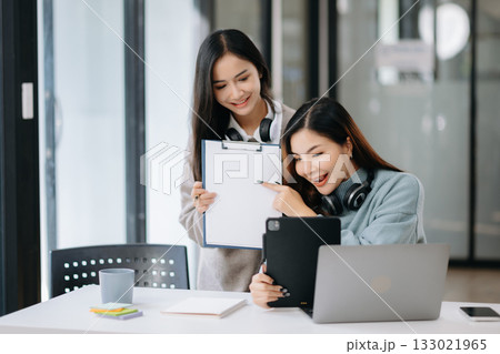 Two young Asian female college students working on the school project using laptop computer and tablet together Two young Asian female college students working on the school project using laptop computer and tablet together 133021965