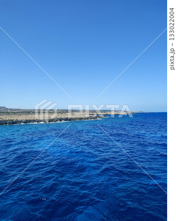 The Stunning Blue Ocean is complemented with Clear Skies above and a Rocky Shoreline nearby 133022004