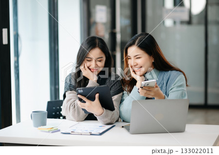 Two business workers talking on the smartphone and using laptop at modern office. 133022011