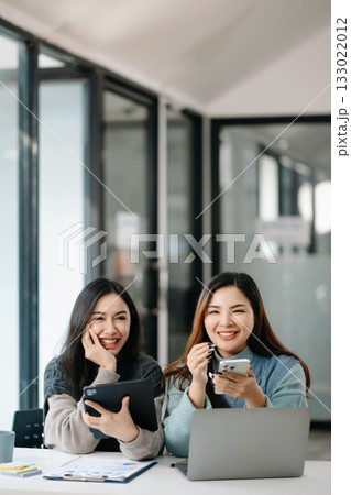 Two business workers talking on the smartphone and using laptop at modern office. 133022012