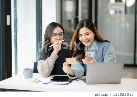 Two business workers talking on the smartphone and using laptop at modern office. Two business workers talking on the smartphone and using laptop at modern office. 133022013