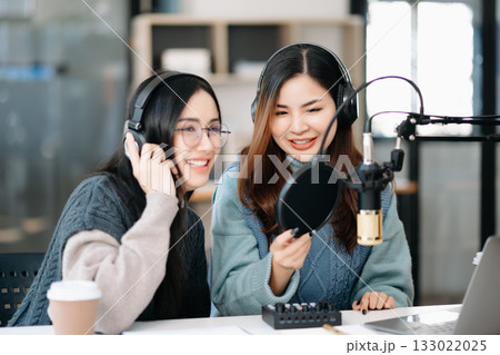 Young woman and Asian woman wearing headphones and doing a live podcast for their channel, communication for radio podcast and technology concept 133022025