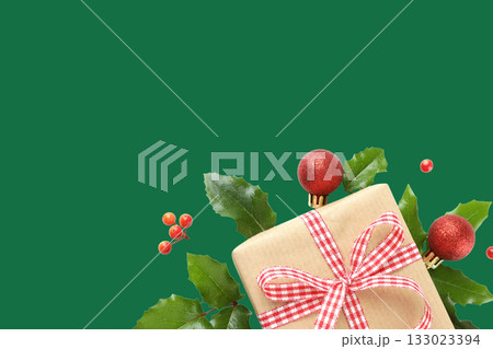 Gift with red ribbon among holly and ornaments 133023394