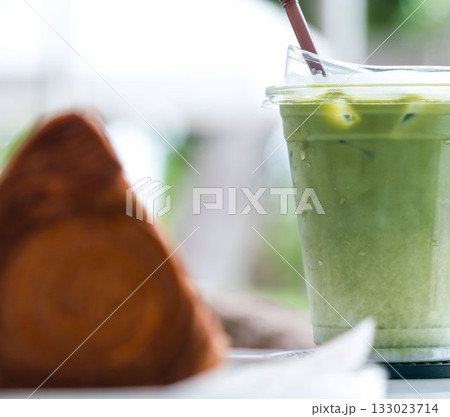 Iced matcha drink and croissant on table at cafe Iced matcha drink and croissant on table at cafe 133023714