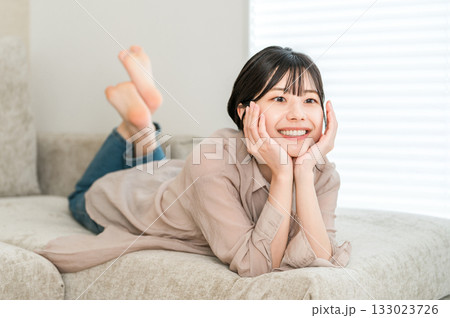 ソファーに寝そべってくつろぐ若いアジア人女性 ソファーに寝そべってくつろぐ若いアジア人女性 133023726