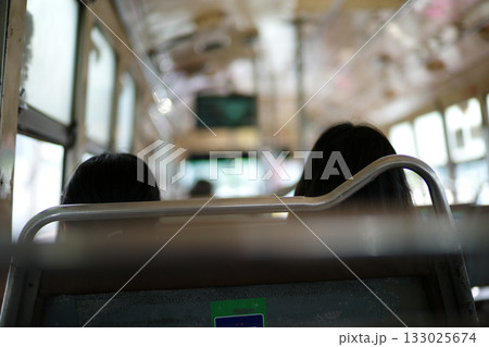 Rear view of two passengers sit inside the traditional public bus in Bangkok 133025674