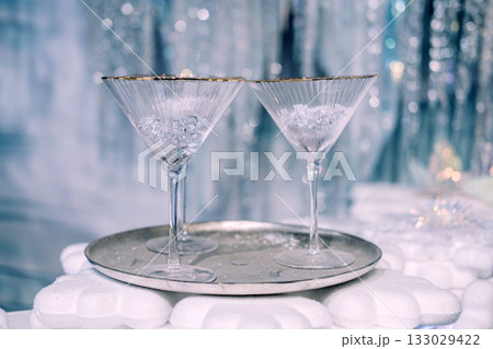 Two elegant martini glasses with crushed ice on a silver tray in a festive winter-themed setting. Holiday celebration styling, Christmas entertaining, minimal luxury decor, frosted seasonal aesthetic Two elegant martini glasses with crushed ice on a silver tray in a festive winter-themed setting. Holiday celebration styling, Christmas entertaining, minimal luxury decor, frosted seasonal aesthetic 133029422