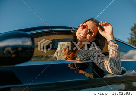 stylish commuter adjusting sunglasses during sunset drive stylish commuter adjusting sunglasses during sunset drive 133029936