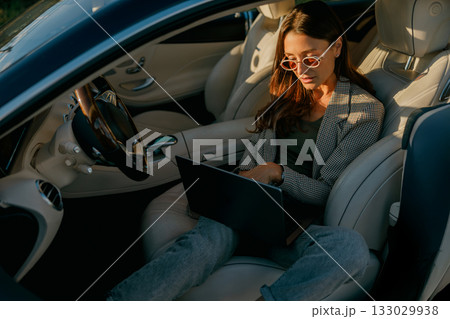 Woman balances laptop and coffee in vehicle workspace scene 133029938