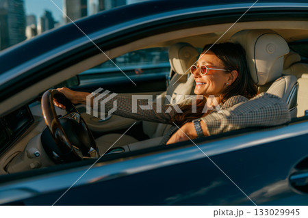 Calm evening journey as woman observes cityscape at sunset Calm evening journey as woman observes cityscape at sunset 133029945