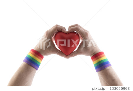 Red heart in hands with colorful rainbow LGBT wristband isolated on white background with clipping path.  133030968