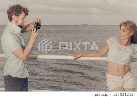Young couple in love is taking photos on sea pier. 133031212