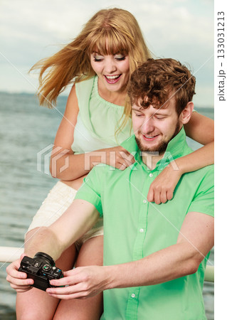 Young couple in love is taking photos on sea pier. Young couple in love is taking photos on sea pier. 133031213