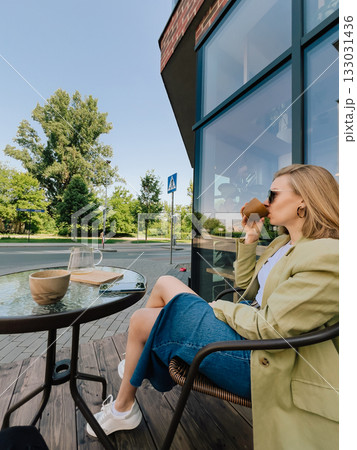 Young businesswoman sitting at table outside bustling cafe, sipping coffee and soaking in vibrant atmosphere during well deserved break on sunny day. Elegant girl enjoying coffee break at outdoor cafe Young businesswoman sitting at table outside bustling cafe, sipping coffee and soaking in vibrant atmosphere during well deserved break on sunny day. Elegant girl enjoying coffee break at outdoor cafe 133031436