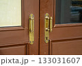Close-up of old brass door handles with patina on a brown wooden front door. Vintage background for the concept of entrance, security, opportunity, and decision making for the future. 133031607