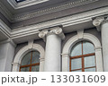 Facade fragment of an old classicism style building with Ionic columns and an arched window. Architectural background symbolizing justice, government, education, or culture and finance. 133031609