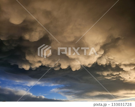 Storm clouds on sunset. Light in the dark and dramatic storm clouds. Background of storm clouds before a thunderstorm. Mammatus clouds 133031728